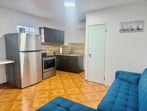 A compact kitchen with a refrigerator, oven, and dark cabinets. - Ocean Escape with Balcony, Pool, Patio & BBQ Fun (Cabo Rojo)