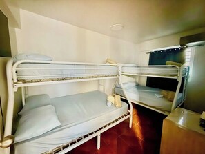 A room with two bunk beds, a small table, and a television. - Ocean Escape with Balcony, Pool, Patio & BBQ Fun (Cabo Rojo)