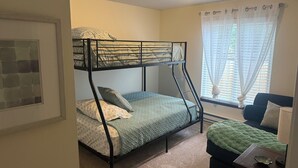 A bunk bed with a headboard, a bedside table with a lamp, and a window with curtains. - Welcome to Mountain Mist Lodge! (Fort Collins)