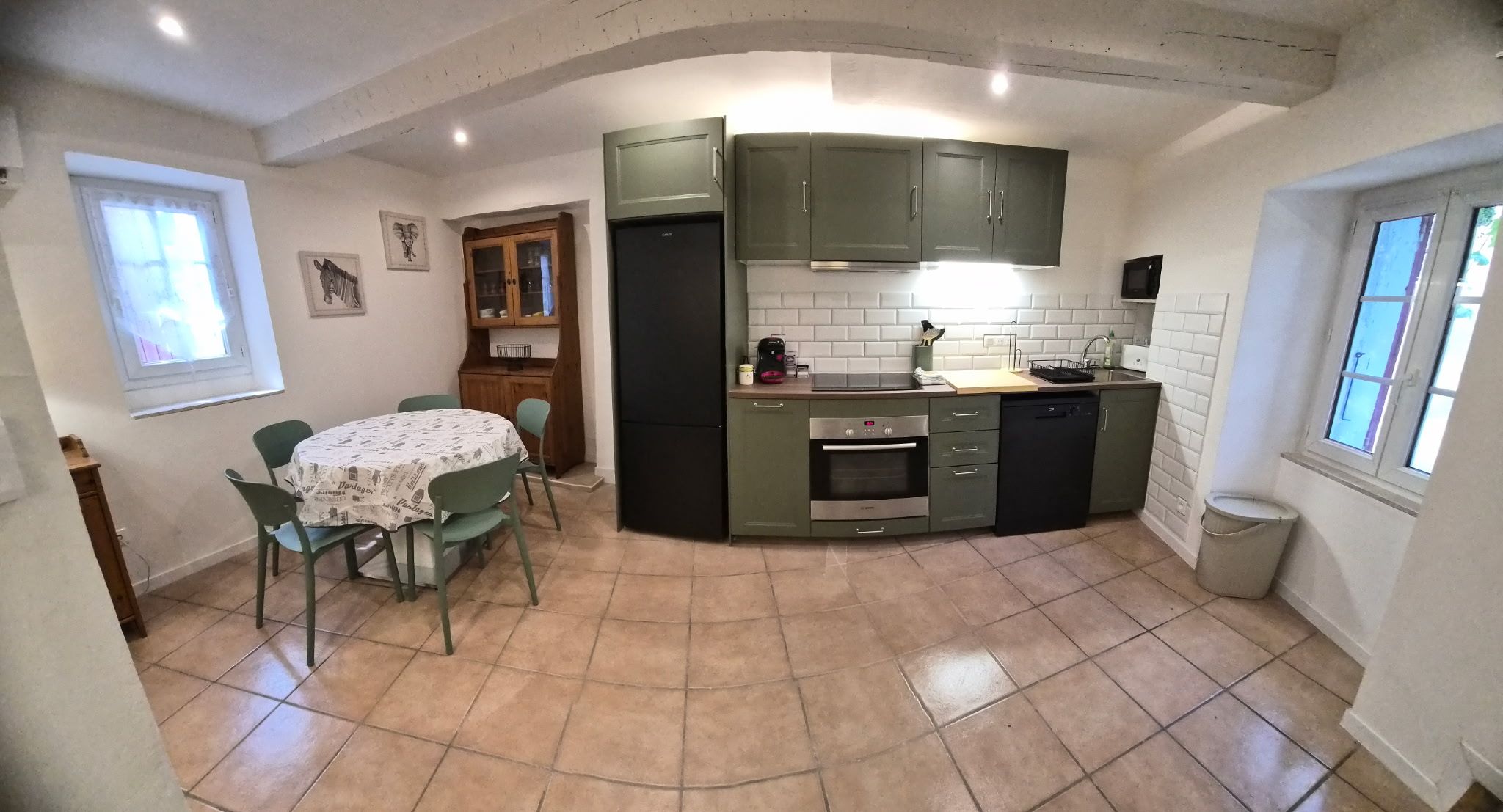 A compact kitchen with a dining table, chairs, and a built-in oven.