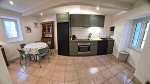 A compact kitchen with a dining table, chairs, and a built-in oven. - Village house for 5 people. (Peyruis)