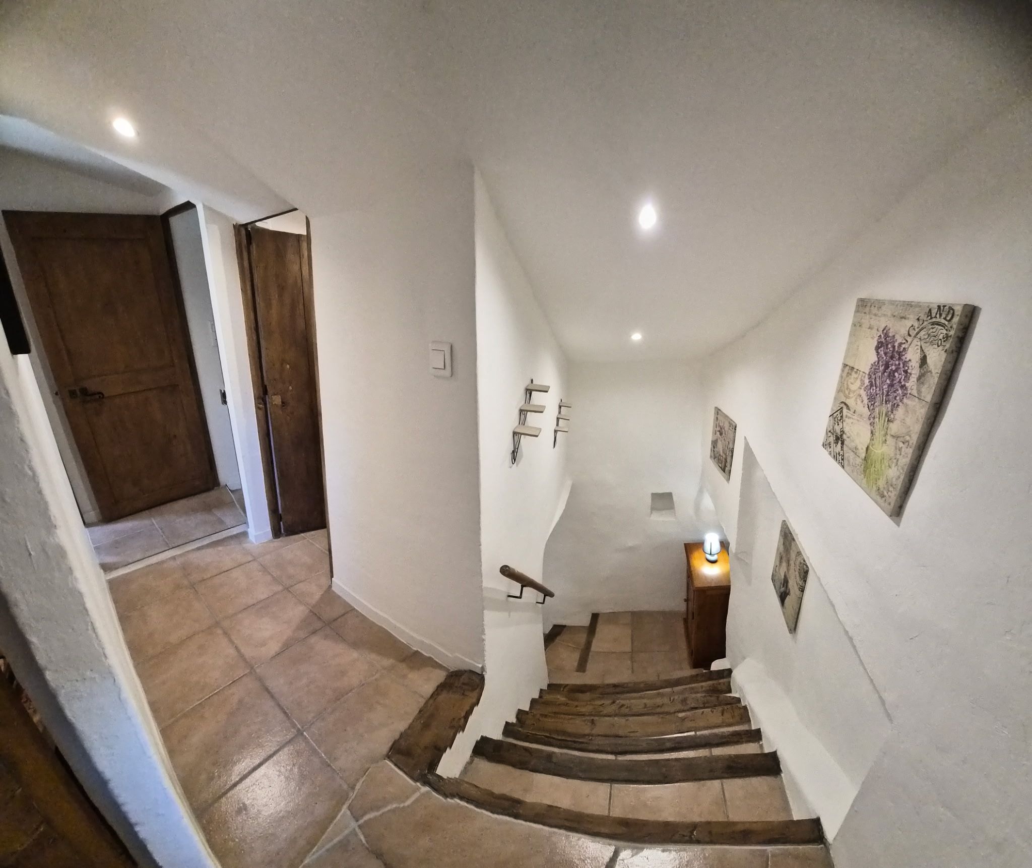 A staircase with a handrail, a light fixture at the top, and a door at the bottom.