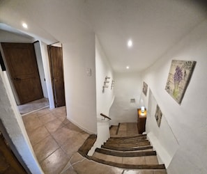A staircase with a handrail, a light fixture at the top, and a door at the bottom.