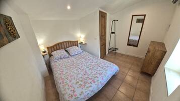 Ein Schlafzimmer mit einem Bett, Nachttischlampen, einem Holzschrank, einem Spiegel und einer Tür.