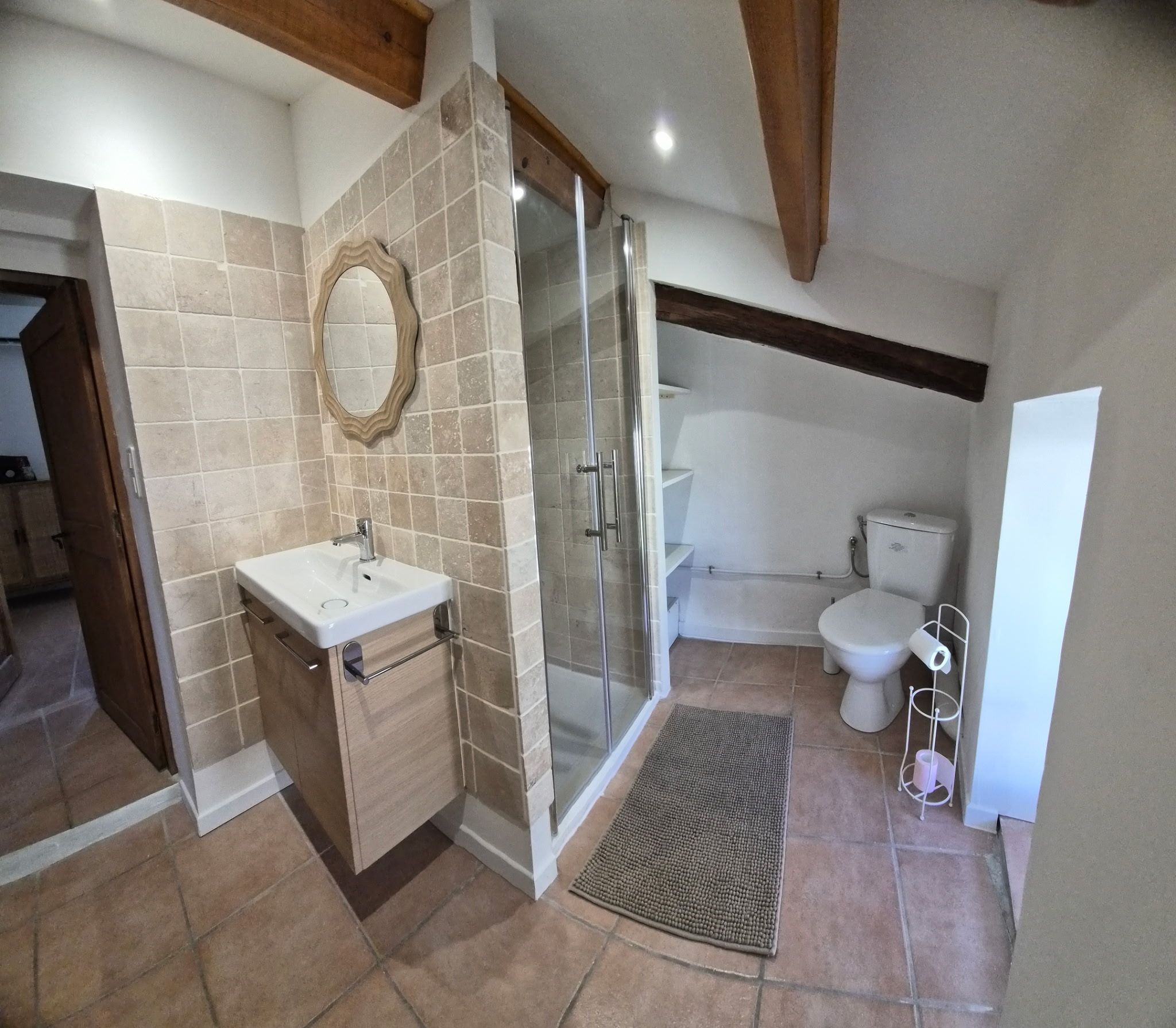 Een badkamer met douche, toilet en wastafel.