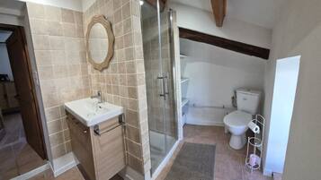 Een badkamer met douche, toilet en wastafel.