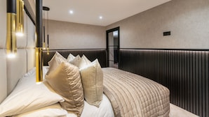 A modern bedroom with a bed, pillows, a headboard, and a wall-mounted light fixture.