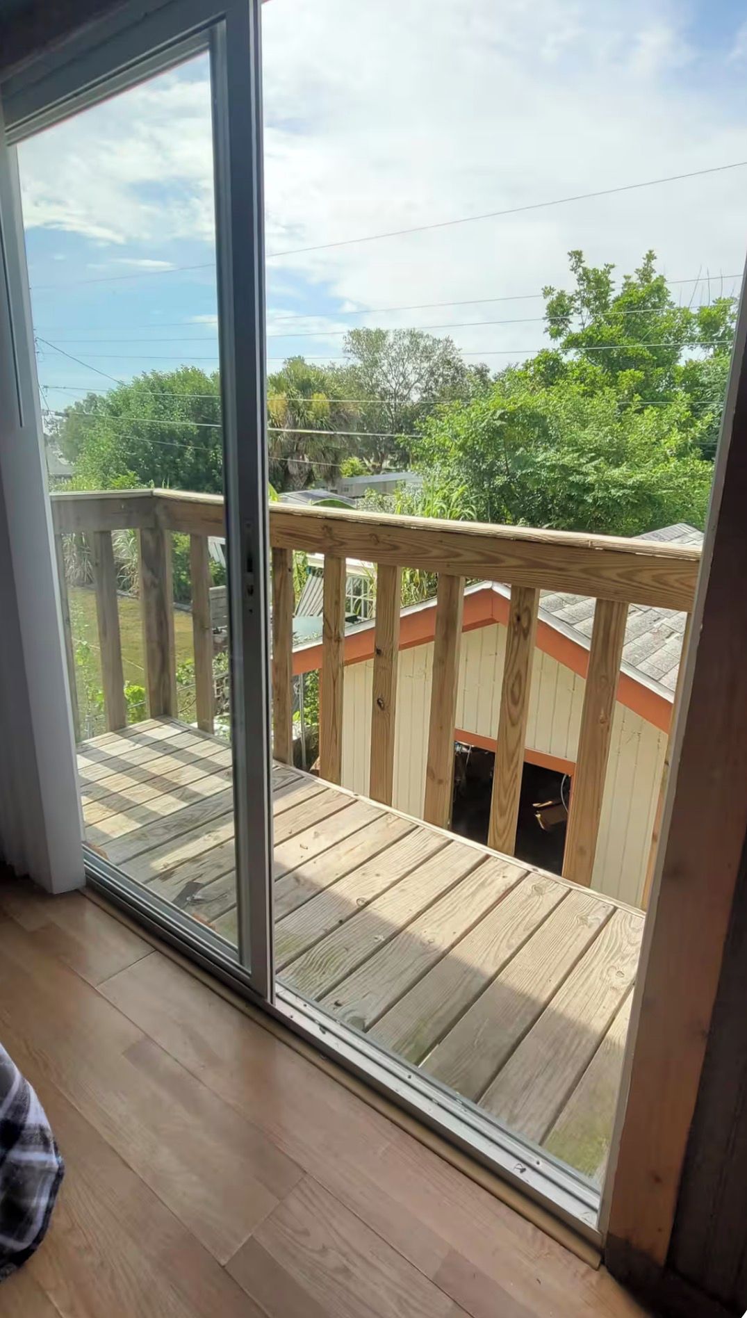 A room with a sliding glass door leading to an outdoor deck with a wooden railing.