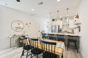 A modern kitchen with white cabinets, a central island, and pendant lighting. - Pristine New 2BR Townhome | South College Station (College Station)