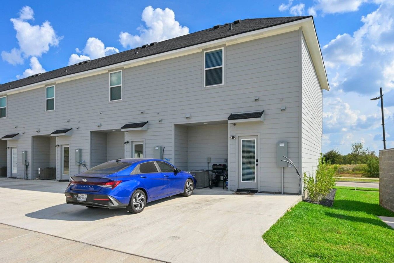 A multi-story residential building with a blue car parked in front.