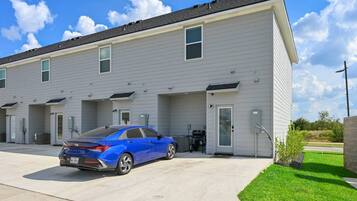 A multi-story residential building with a blue car parked in front.
