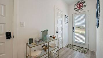 A hallway with a door, a coat rack, a coffee maker, and a framed picture.