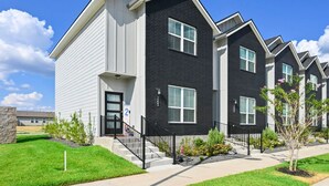 Fileira de edifícios de apartamentos modernos, com um estilo arquitetônico uniforme, combinando revestimento branco e escuro, grandes janelas e um gramado bem cuidado.