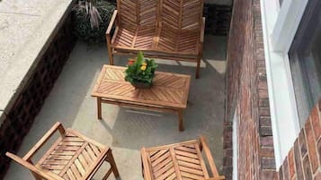 An outdoor patio with a table and four chairs, a large umbrella, and a brick wall.