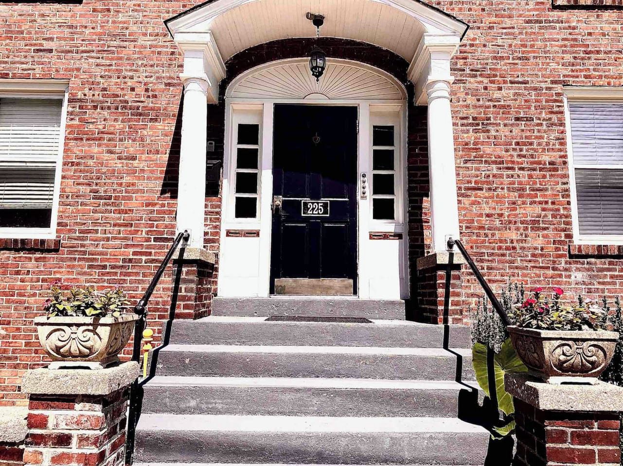 Un bâtiment en briques avec une porte noire, des moulures blanches et le numéro « 225 » sur la porte.