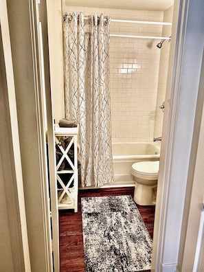 Ett badrum med dusch, toalett och handduksställ.