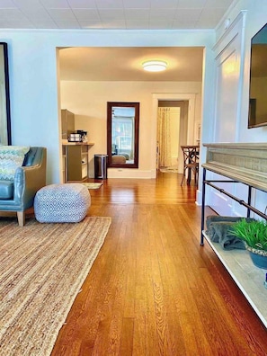 A modern living room with hardwood flooring, a sofa, a patterned ottoman, and a coffee table. - Broadway BNBs III - 1 BR Apartment -Walk to Centre (Danville)