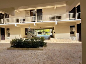 A building with a covered courtyard, a statue, and a pool in the background. - Bright Coastal Stay Near Beach w/ Pool & Tennis (Boquerón)