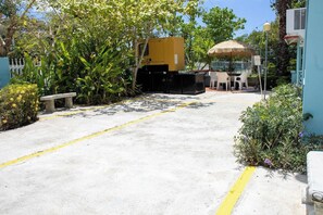 A parking area with a yellow line, a concrete bench, and a thatched umbrella. - 11BR Coastal Retreat with Pool and Beach Access (Boquerón)