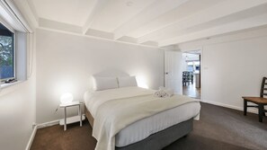 Une chambre avec un grand lit, une table de chevet avec une lampe et une vue sur la salle à manger.