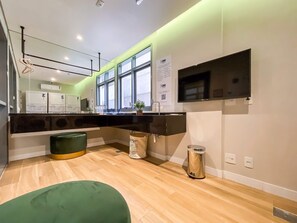 Une cuisine moderne dotée d’une grande fenêtre, d’appareils électroménagers intégrés et d’un coin salon agrémenté de plantes vertes.