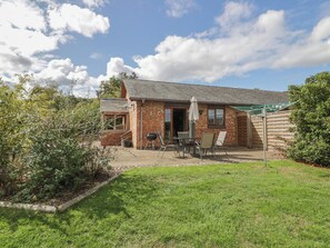 A brick building with a patio area, outdoor seating, and a grill. - Bramley Bungalow (Worcester)