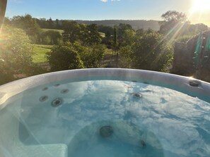 A hot tub with a clear view of a lush garden and distant hills. - Bramley Bungalow (Worcester)
