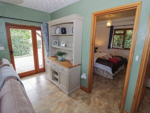 A room with a bed, a sofa, a kitchenette, and a view of the outdoors. - Bramley Bungalow (Worcester)