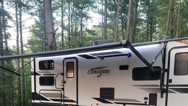 Ein Wohnmobil mit Tisch und Grill in bewaldeter Landschaft.