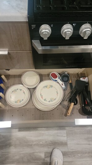 A kitchen with a stove, three plates, a spoon, and a spatula.