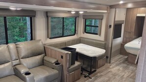 Ein kompaktes Wohnmobil-Interieur mit einer Sitzecke, einem kleinen Esstisch und einer Küchenzeile.