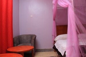A room with a bed, a chair, and a small table.