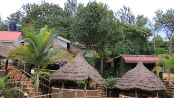 Cabanas com telhado de palha, rodeadas por vegetação e um edifício com telhado vermelho.