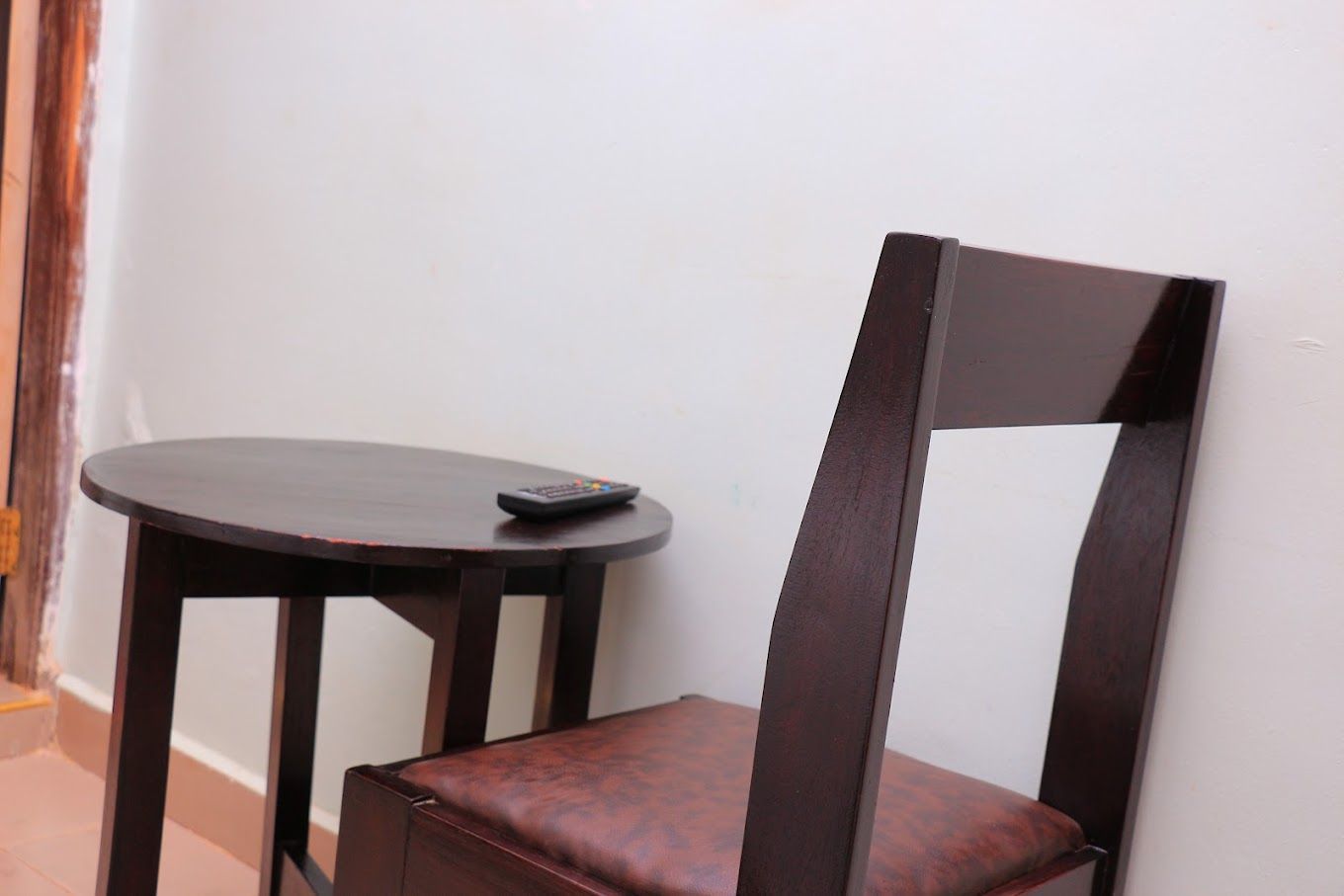 Uma cadeira de madeira com assento acolchoado e uma pequena mesa redonda ao lado.