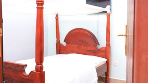 Una cama con dosel y colcha blanca en una habitación con paredes azul claro y una puerta cerrada.