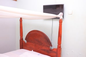 Una cama con cabecera de madera y dosel.