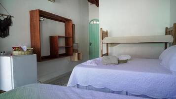 Un dormitorio con dos camas, cabecera de madera, un espejo y una puerta verde.