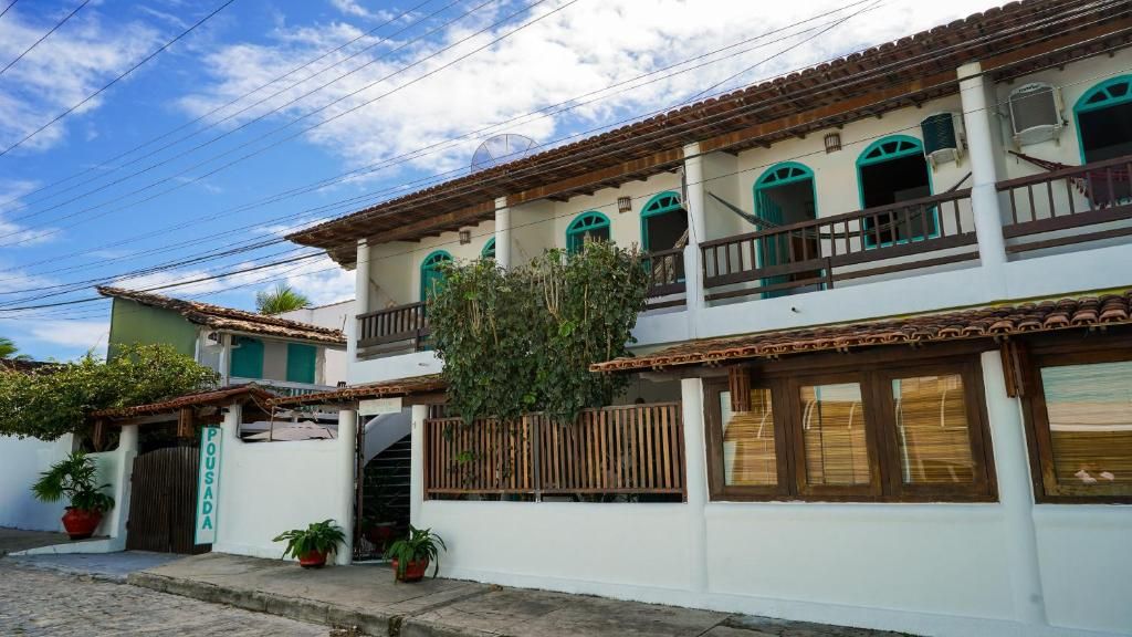 Un edificio de dos pisos con balcón, cerca de madera y plantas en macetas.