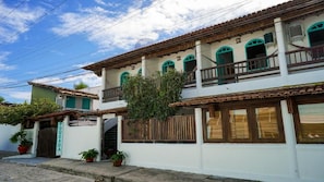 A two-story building with a balcony, a wooden fence, and potted plants. - Pousada Coração do Arraial (Porto Seguro)