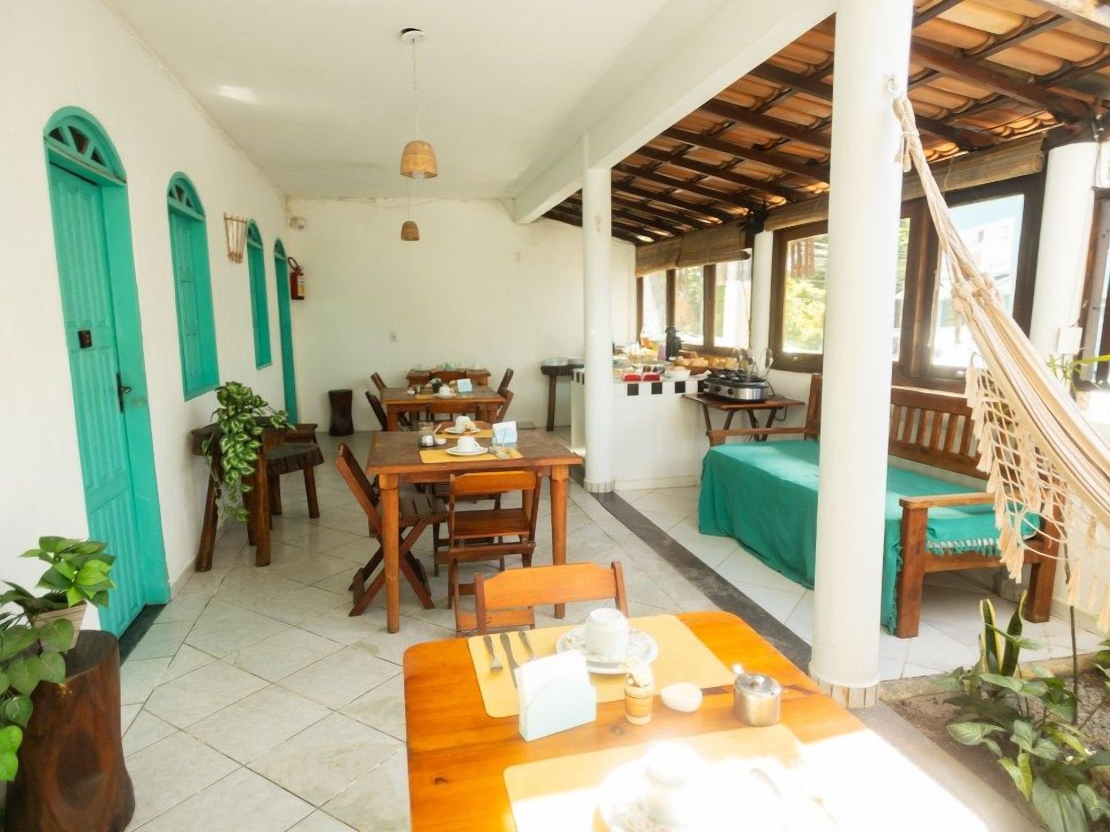 Un comedor con mesas y sillas de madera, una zona de cocina con estufa, y una escalera que conduce a un balcón.