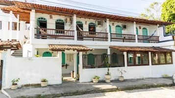 Un edificio de dos pisos con balcón, plantas en macetas y un letrero que dice 'POSADA'.