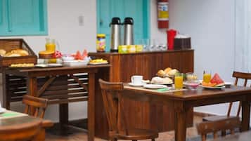 A wooden dining table with breakfast items, a fire extinguisher, and teal-colored doors in the background.