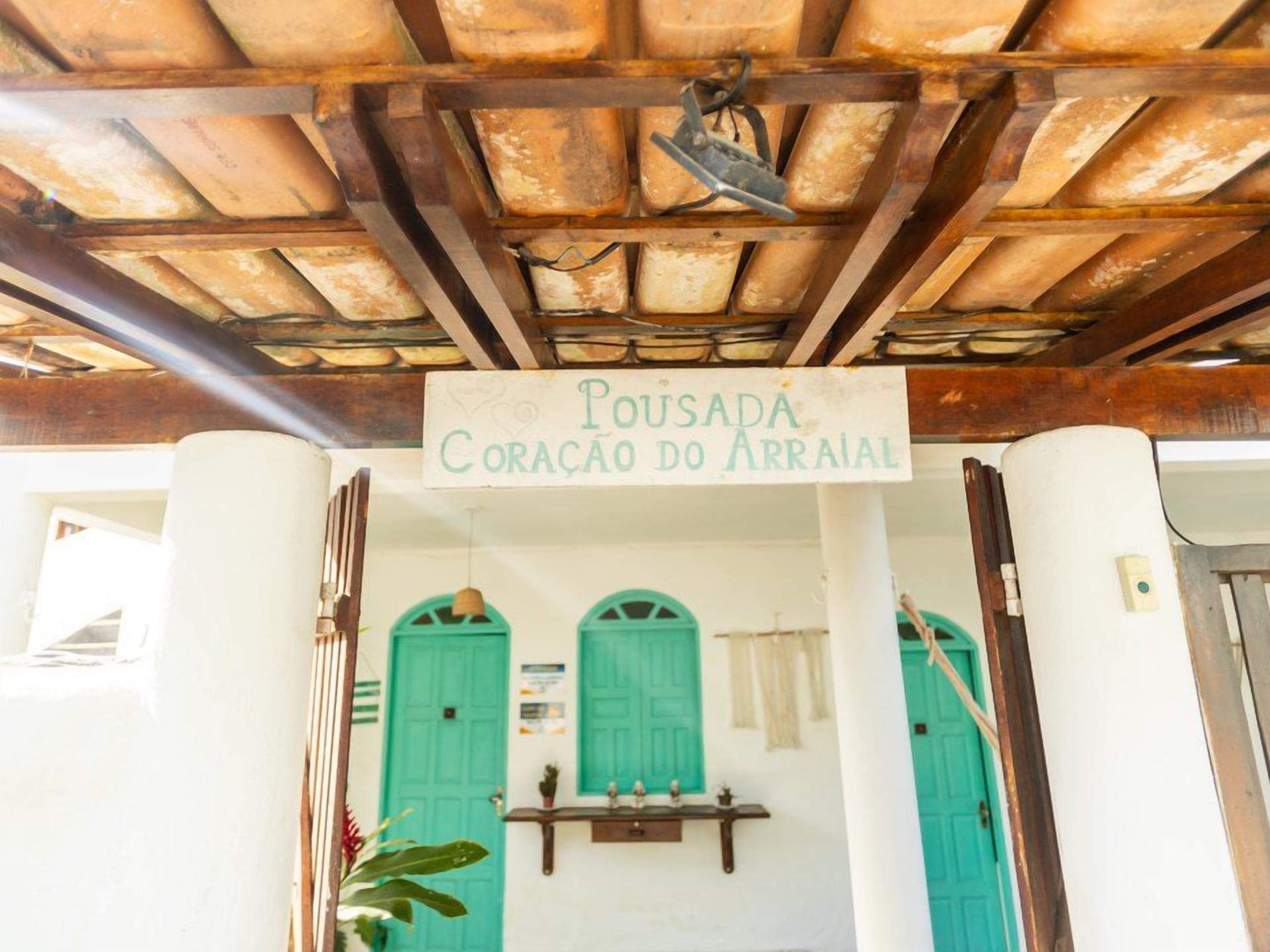 Entrada de um edifício com uma placa indicando 'Pousada Coracao do Arraiol' e teto de madeira.