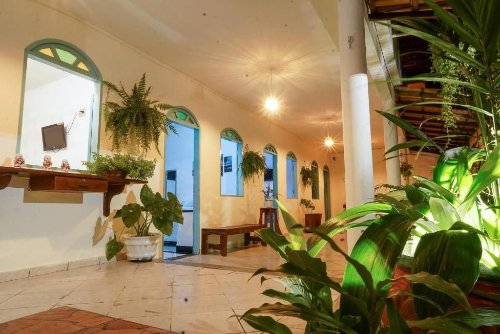 Un vestíbulo de hotel con suelo de baldosas, arcos y plantas en macetas.