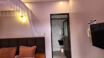 A hotel room with a bed, bedside table, and a TV mounted on the wall.