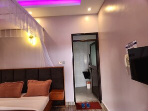 Ein Hotelzimmer mit Bett, Nachttisch und Wandfernseher.