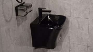 A bathroom with a black sink, a mirror, and a trash bin.