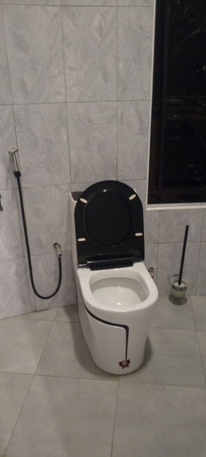 Eine Toilette mit schwarzem Sitz und Deckel, einer Bidet-Funktion und einer Handbrause.