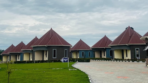 A row of modern buildings with conical roofs, a paved walkway, and a grassy area. - Ihunde Farm Lodge (Kiruhura)