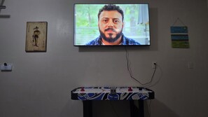 A television mounted on a wall, a framed picture, and a small table with a cable.